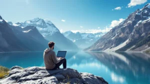 Person working on a laptop with a stunning scenic backdrop of mountains and a lake, symbolizing the freedom and flexibility of the digital nomad lifestyle.